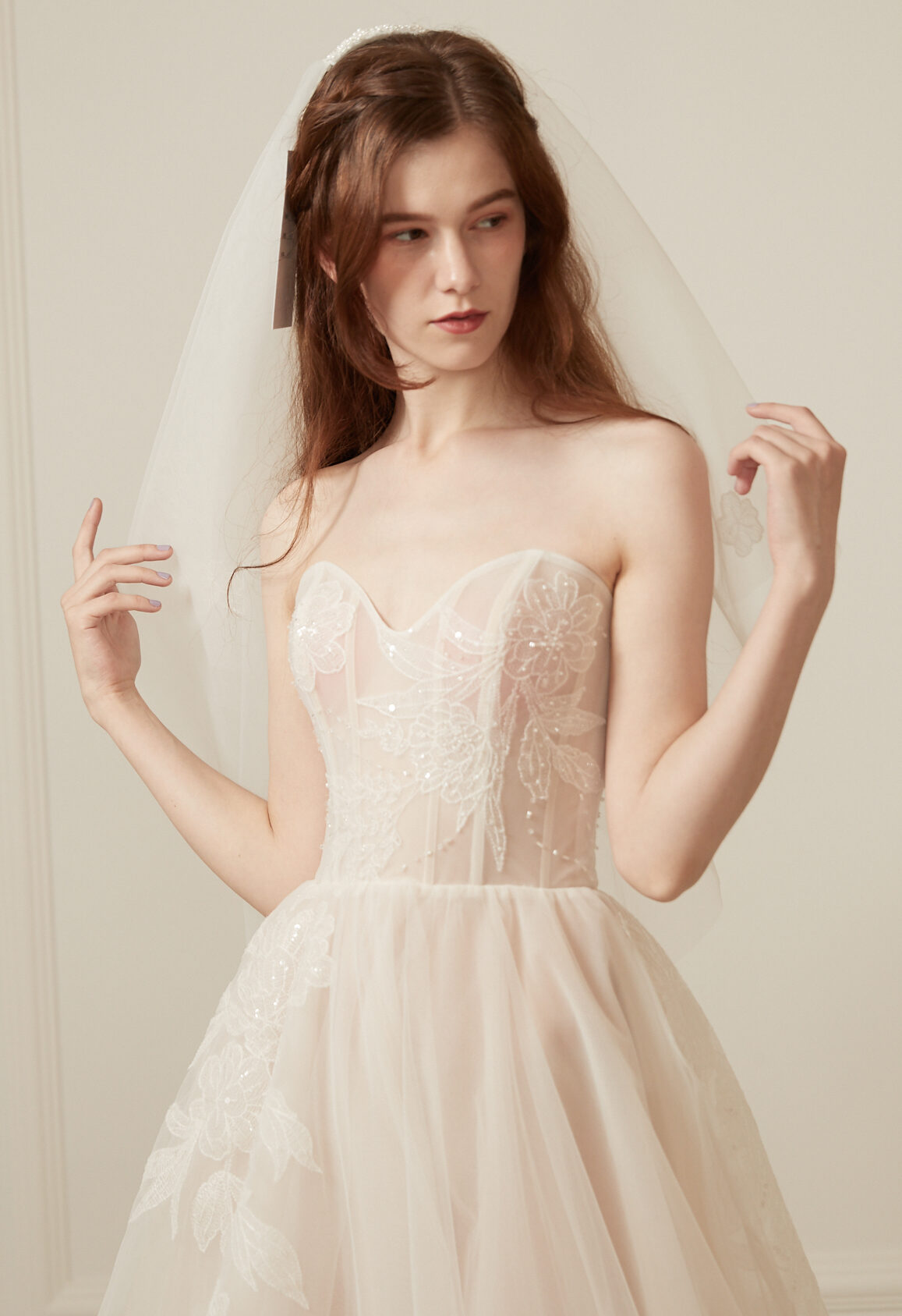 Ethereal strapless A-line wedding dress with a lace bodice and flowing champagne tulle skirt, perfect for a romantic wedding.